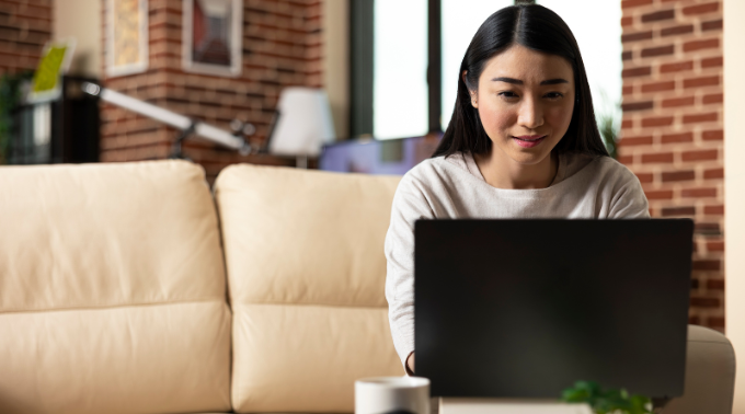 Freelancer working on a laptop in a home office environment with headphones and notebook on the table.